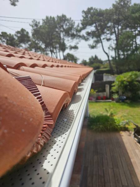 Gouttières blanches avec descentes et parafeuilles sur une maison à Mimizan