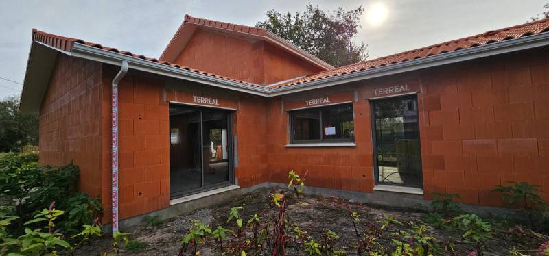 Installation de gouttières G300 blanches avec descentes 60x80 pour la façade d’une maison située à Biscarrosse