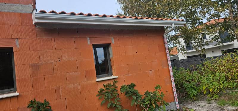 Installation de gouttières G300 blanches avec descentes 60x80 de qualité pour la façade d’une maison située à Biscarrosse