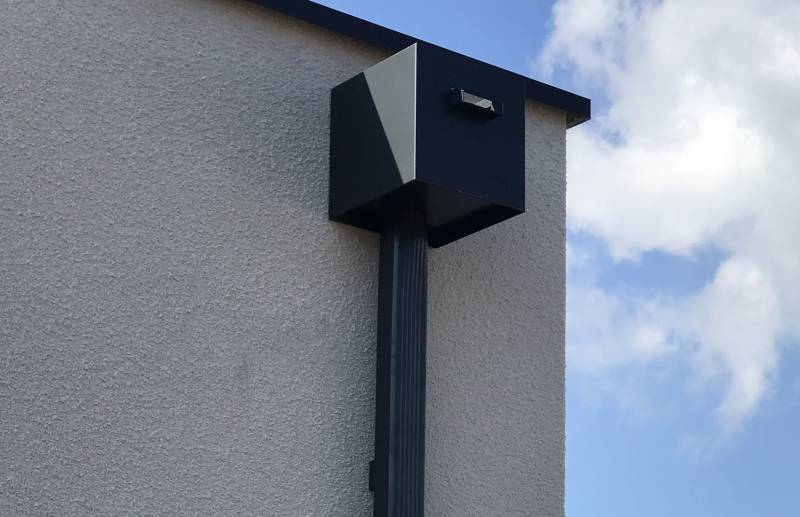 Installation d'une boîte à eau pluviale grise en aluminium pour un toit plat à Biscarrosse