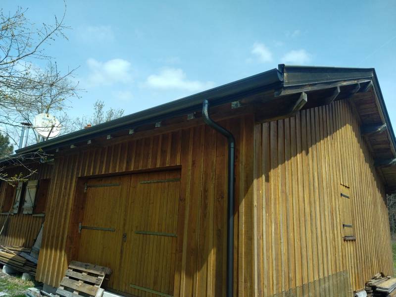 Gouttières et descentes noires graphite sur un gîte en bois à Moustey