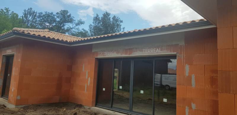 Installation de gouttières G300 et de leurs descentes bleu ardoise sur une maison en construction aux alentours d’Orx